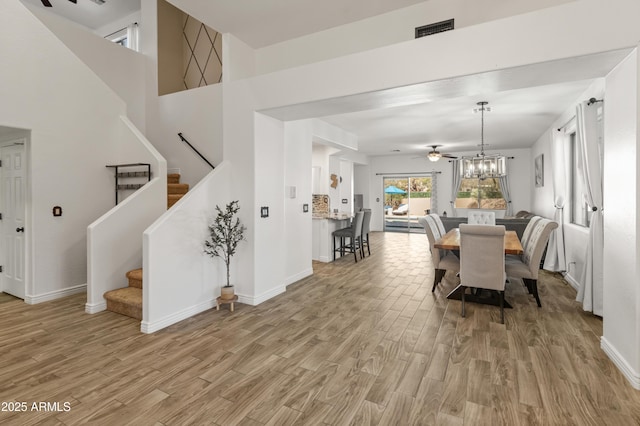 dining area featuring light wood-style flooring, visible vents, stairway, and baseboards