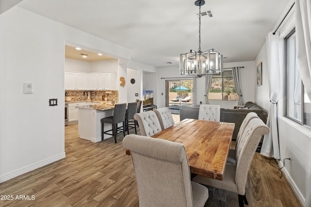 dining room featuring light wood-type flooring, visible vents, baseboards, and an inviting chandelier