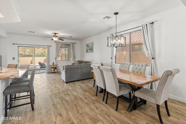 dining room featuring light wood finished floors, baseboards, visible vents, and ceiling fan with notable chandelier