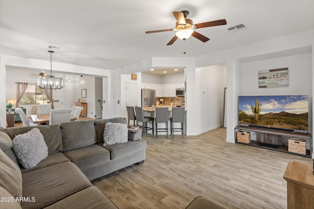 living area featuring recessed lighting, visible vents, light wood finished floors, and ceiling fan with notable chandelier