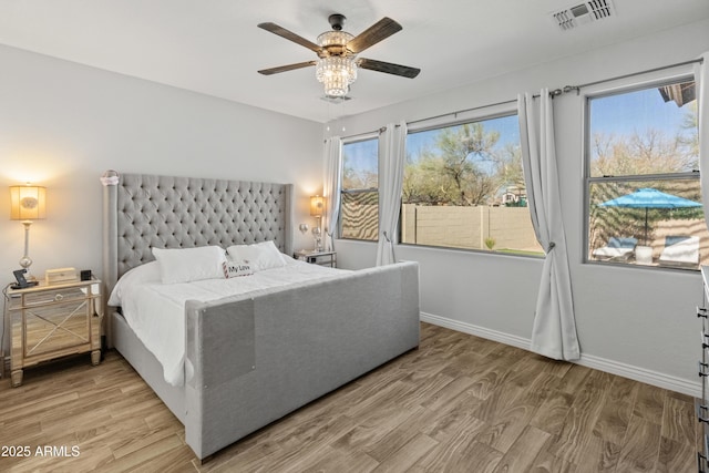 bedroom featuring light wood-type flooring, baseboards, visible vents, and ceiling fan