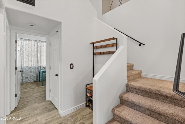 stairway featuring visible vents, baseboards, and wood finished floors