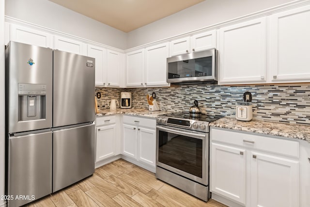 kitchen featuring stainless steel appliances, white cabinetry, and decorative backsplash