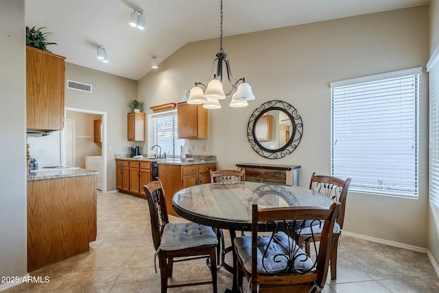 tiled dining space featuring lofted ceiling, sink, and an inviting chandelier