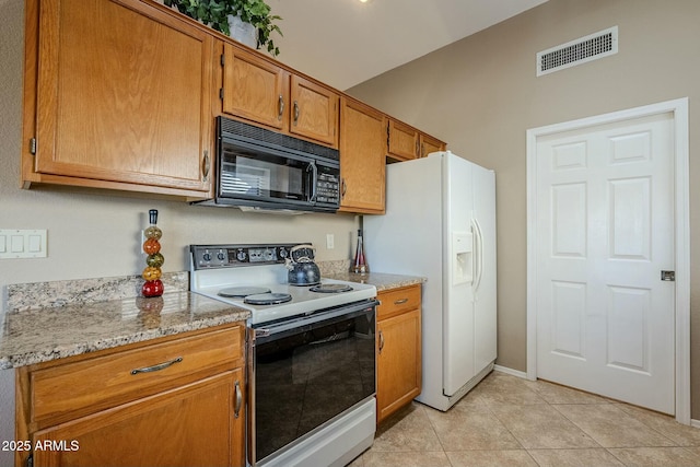 kitchen featuring light stone counters, white appliances, and light tile patterned floors