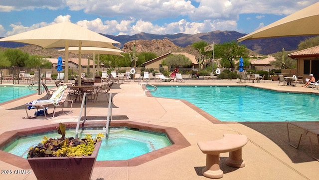 view of pool with a mountain view, a patio, and a hot tub