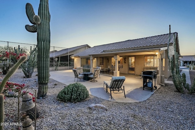 back house at dusk featuring a patio and an outdoor fire pit