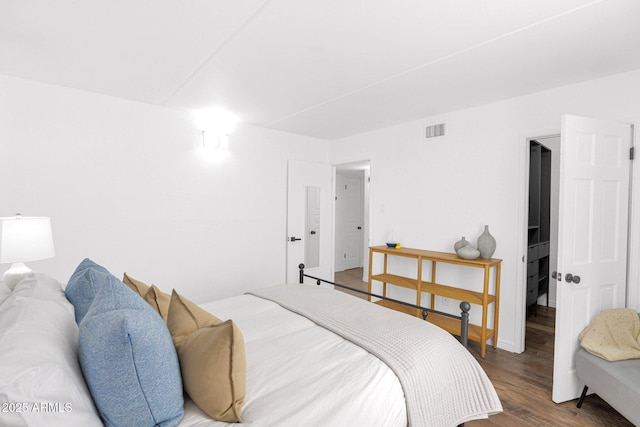 bedroom featuring wood finished floors, visible vents, and baseboards