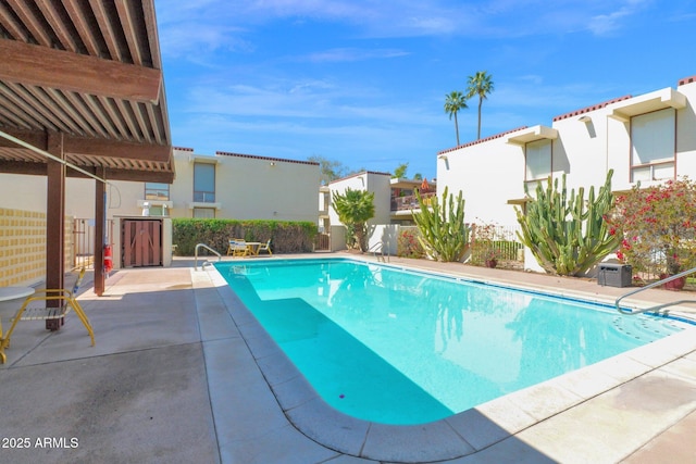 community pool with a patio, fence, and a residential view