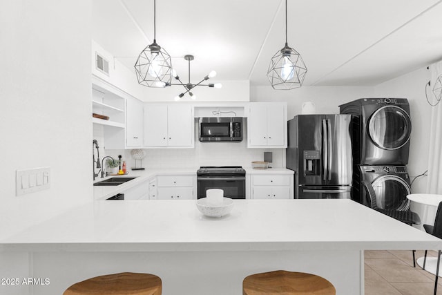 kitchen with stacked washer and clothes dryer, open shelves, appliances with stainless steel finishes, a peninsula, and light countertops