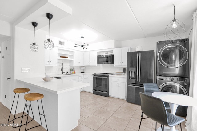 kitchen featuring a peninsula, open shelves, stainless steel appliances, decorative backsplash, and stacked washer / drying machine