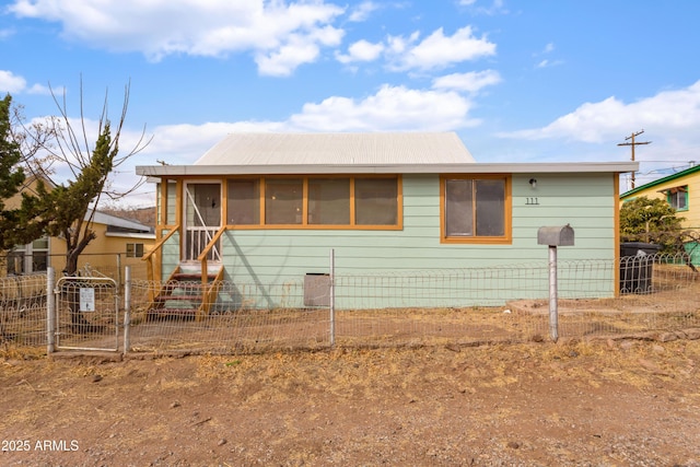 view of front of home featuring entry steps, a sunroom, and fence