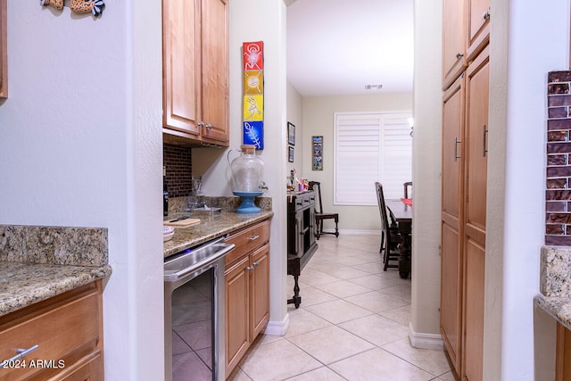 kitchen with light tile patterned flooring, stone countertops, and beverage cooler