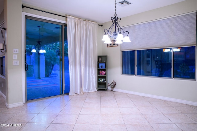 empty room with light tile patterned floors and a chandelier