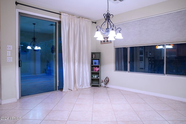 spare room featuring tile patterned flooring and a notable chandelier