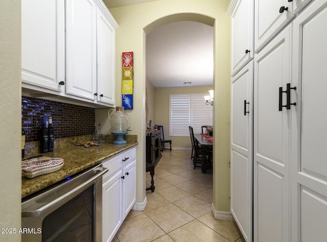 kitchen featuring white cabinetry, dark stone countertops, light tile patterned floors, and beverage cooler