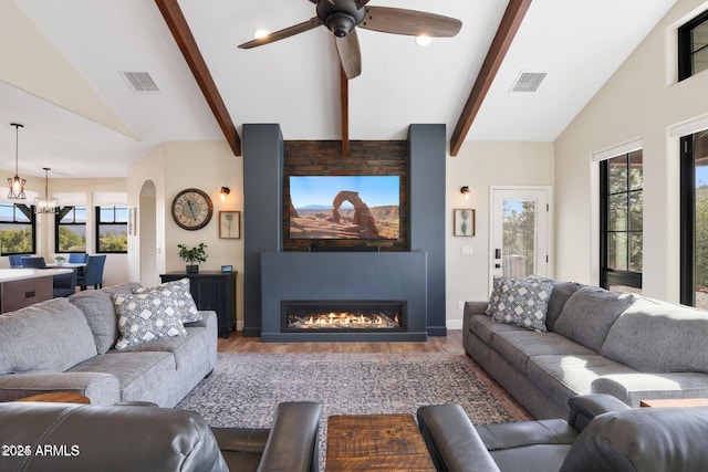 living room featuring hardwood / wood-style flooring, vaulted ceiling with beams, ceiling fan with notable chandelier, and a fireplace