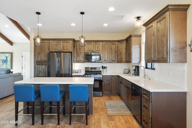 kitchen with pendant lighting, sink, a center island, and appliances with stainless steel finishes