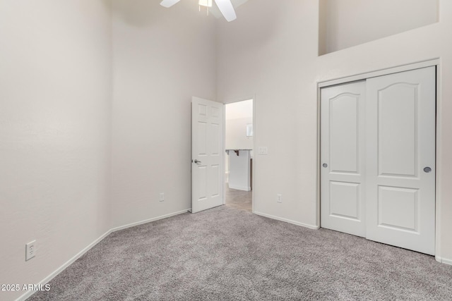 unfurnished bedroom with light carpet, a closet, ceiling fan, and a high ceiling