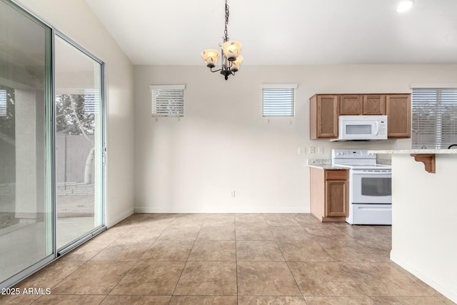 kitchen featuring a healthy amount of sunlight, hanging light fixtures, white appliances, and an inviting chandelier