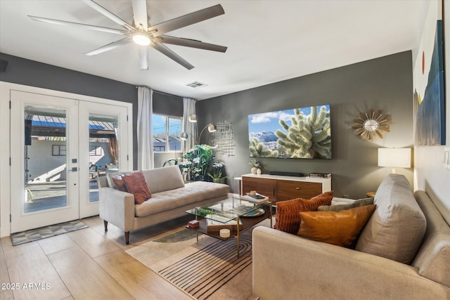 living room with ceiling fan, french doors, and light wood-type flooring