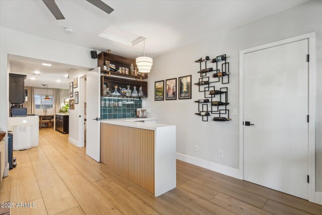 bar with ceiling fan, light hardwood / wood-style floors, and hanging light fixtures