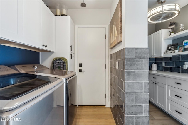 washroom with washer and clothes dryer, cabinets, and light hardwood / wood-style flooring