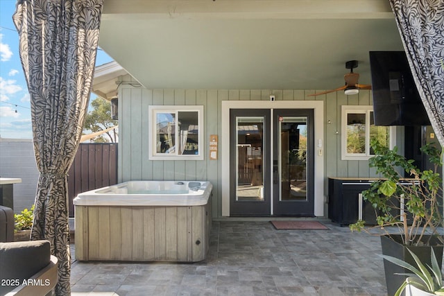 doorway to property featuring ceiling fan, a patio area, french doors, and a hot tub