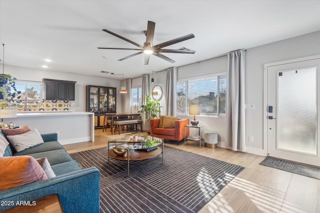 living room with wood-type flooring, ceiling fan, and a healthy amount of sunlight