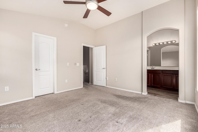 unfurnished bedroom with light colored carpet, connected bathroom, sink, and vaulted ceiling