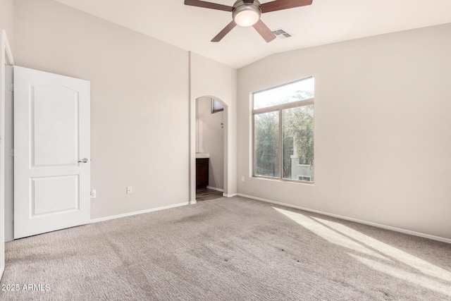 unfurnished bedroom with lofted ceiling, light carpet, connected bathroom, and ceiling fan