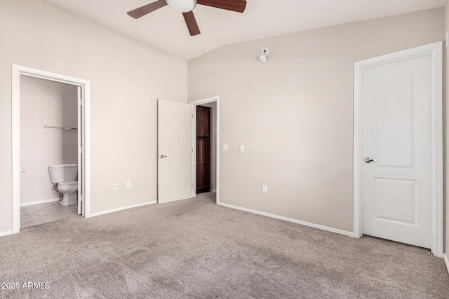 unfurnished bedroom featuring vaulted ceiling, connected bathroom, light carpet, and ceiling fan