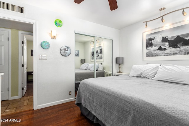 bedroom with baseboards, visible vents, dark wood-style floors, ceiling fan, and a closet