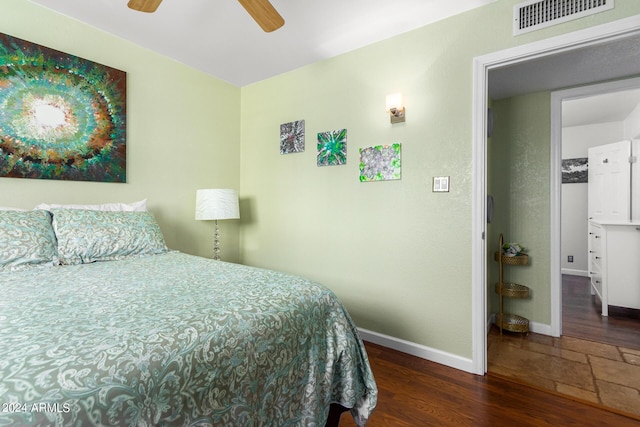 bedroom featuring dark wood-type flooring, visible vents, baseboards, and a ceiling fan