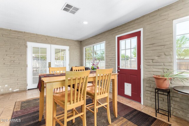 dining room with french doors, stone tile flooring, visible vents, and a healthy amount of sunlight