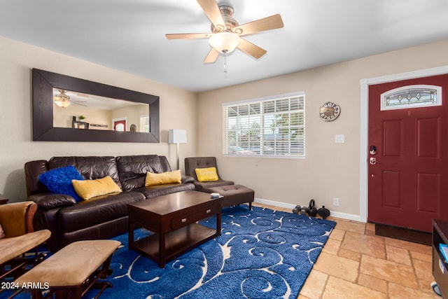 living area with stone tile flooring, ceiling fan, and baseboards