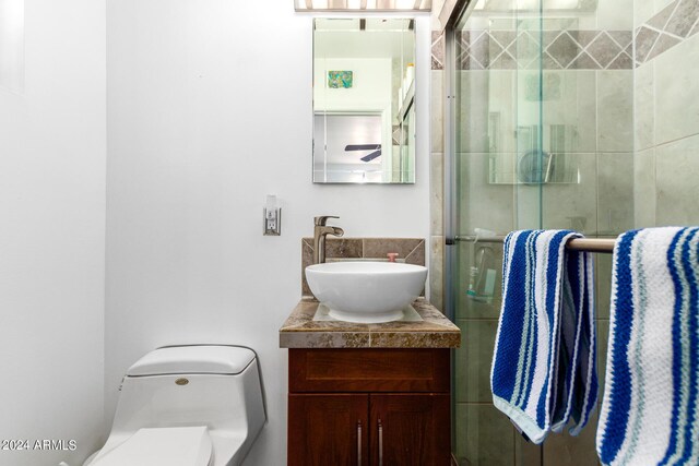 full bathroom featuring a stall shower, backsplash, vanity, and toilet