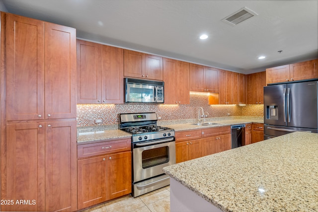 kitchen with light stone countertops, light tile patterned floors, tasteful backsplash, appliances with stainless steel finishes, and sink