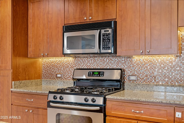 kitchen with stainless steel appliances, light stone countertops, and tasteful backsplash