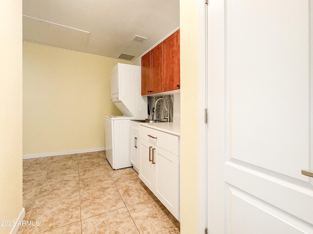 laundry room with stacked washer and clothes dryer, cabinets, sink, and light tile patterned floors