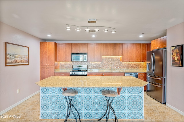 kitchen featuring pendant lighting, backsplash, a breakfast bar area, appliances with stainless steel finishes, and sink