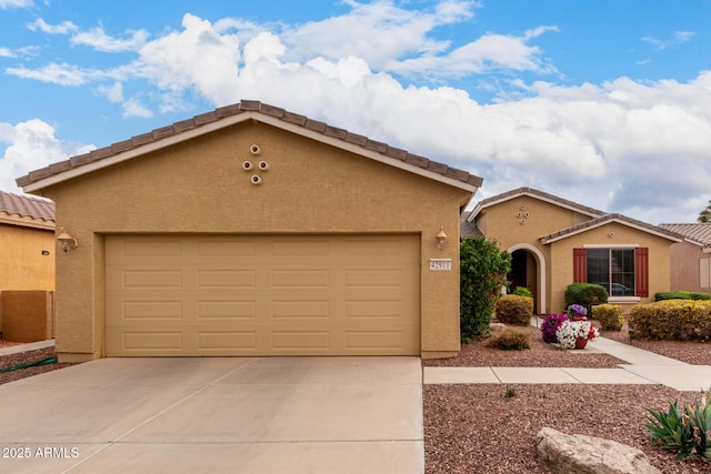 view of front of home featuring stucco siding, a tiled roof, driveway, and a garage