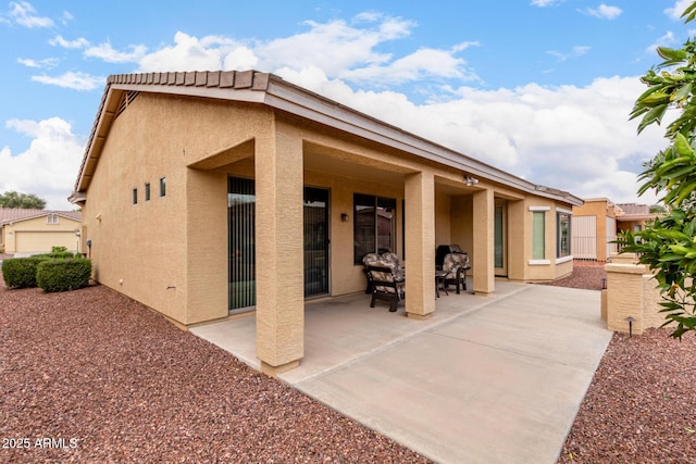 rear view of house featuring a patio and stucco siding