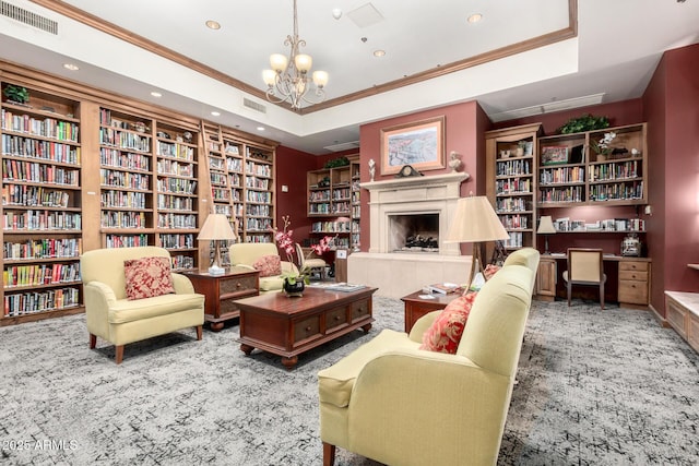 sitting room with a tray ceiling, wall of books, and visible vents