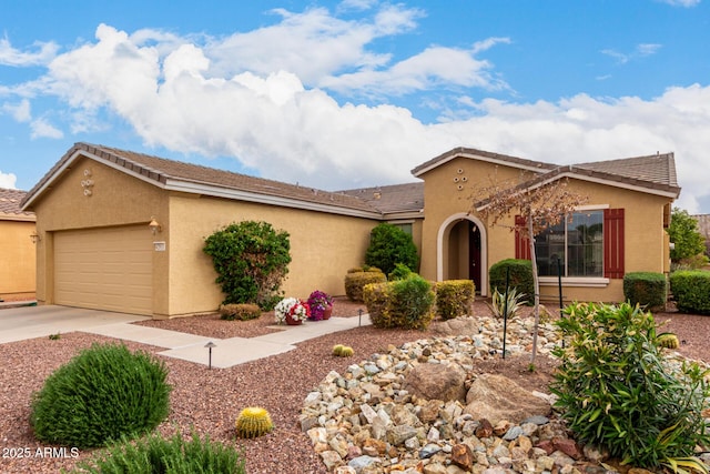 view of front facade with a garage, driveway, and stucco siding