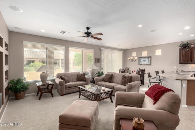 living area with visible vents, baseboards, recessed lighting, light carpet, and ceiling fan with notable chandelier