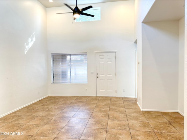 foyer with ceiling fan, light tile patterned floors, and a high ceiling