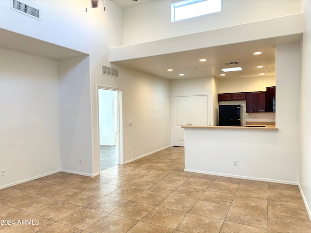 unfurnished living room with a towering ceiling and light tile patterned floors