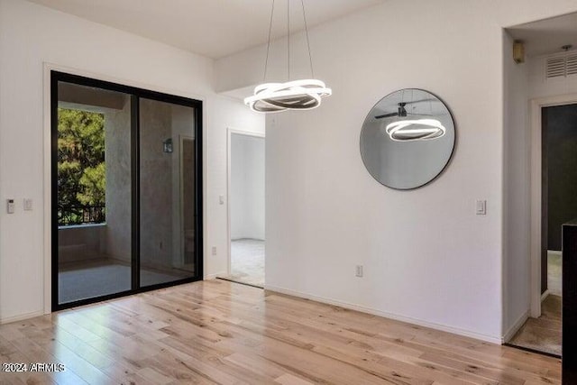 unfurnished dining area with light wood-type flooring and a chandelier