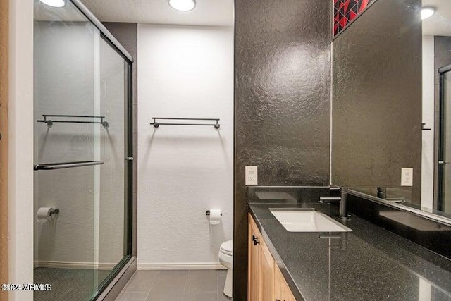 bathroom featuring tile patterned flooring, a shower with door, vanity, and toilet